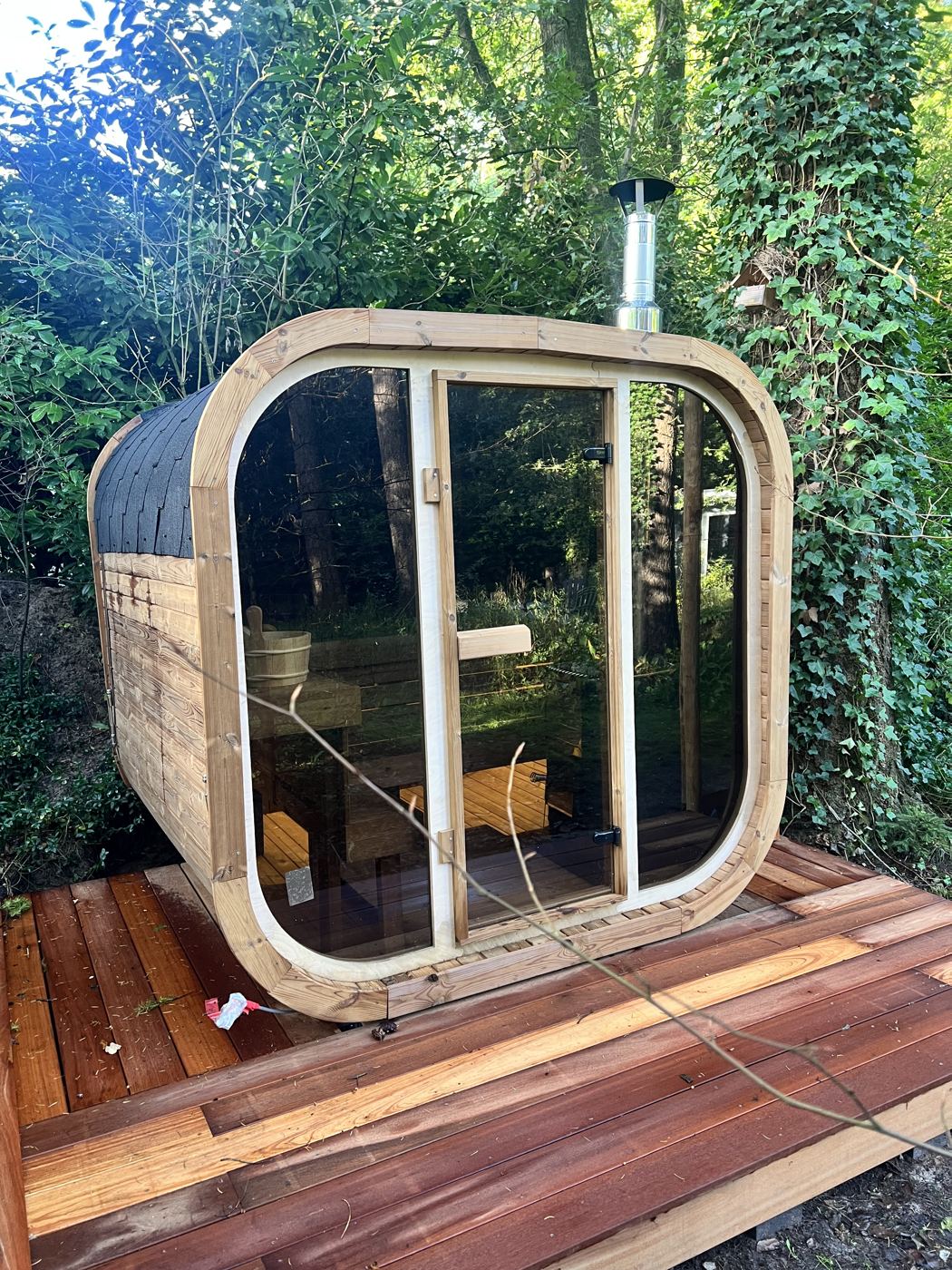 Houtgestookte buitensauna met glazen front in de bostuin